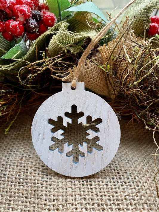 A circular, white wooden Christmas bauble with a snowflake laser cut out the centre 