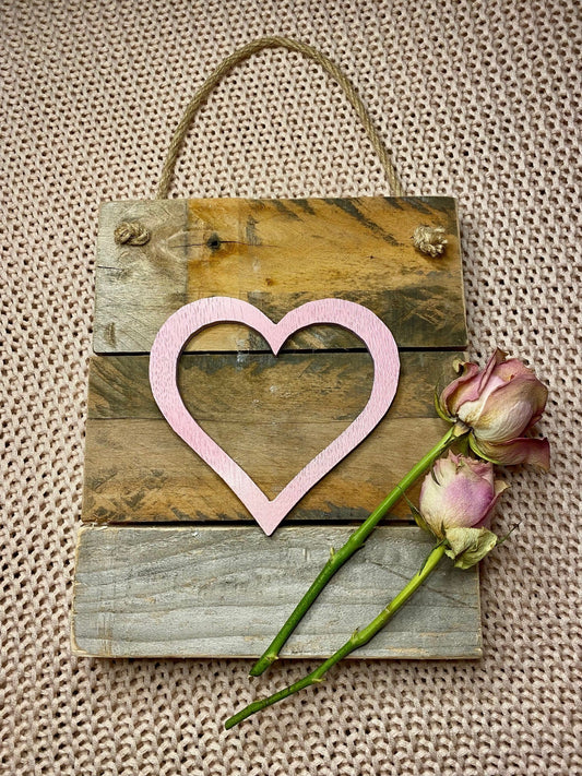 Pink heart on a wooden board with a hanging rope