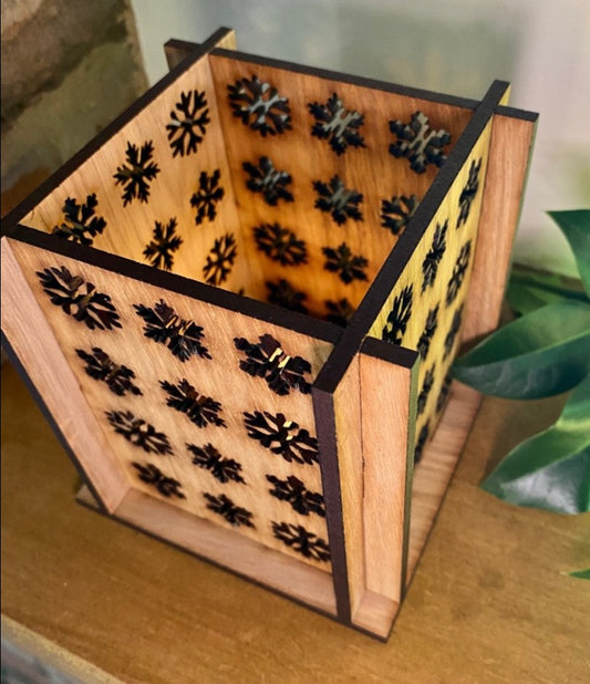 A square lantern with cut out snowflakes and a hole in the bottom to fit over a tea light. Product is slotted together and comes in a range of materials.